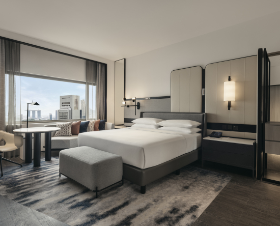 Kamar Tidur Suite Deluxe dengan tempat tidur King dengan Meja dan Kursi Sofa serta Pemandangan Kota dari Jendela Besar